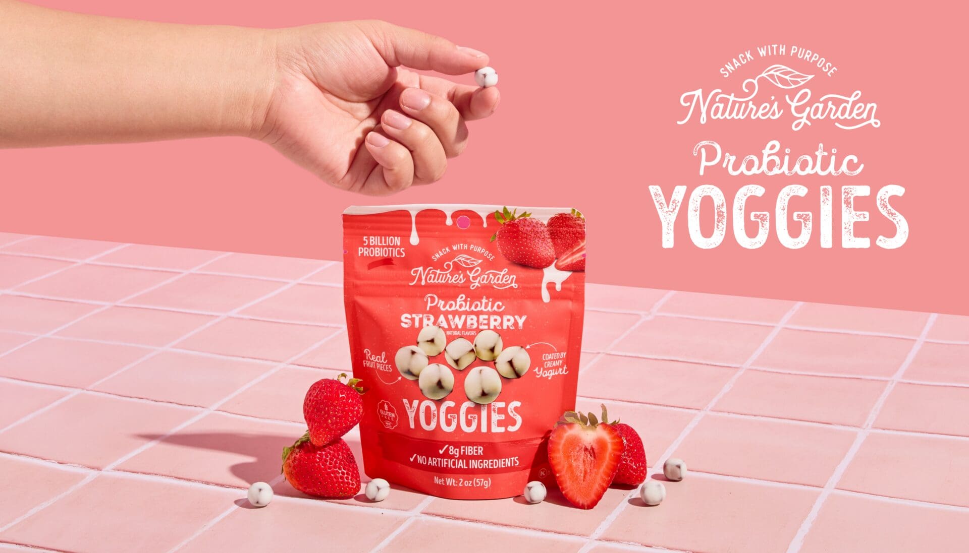 Nature’s Garden Probiotic Strawberry Yoggies pouch with strawberries and a hand holding a yoghurt-coated fruit bite